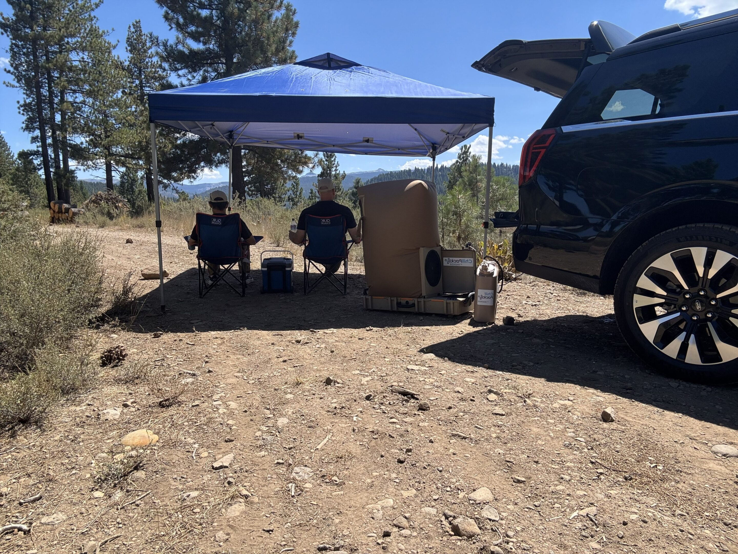 Two people under canopy at outdoor campsite