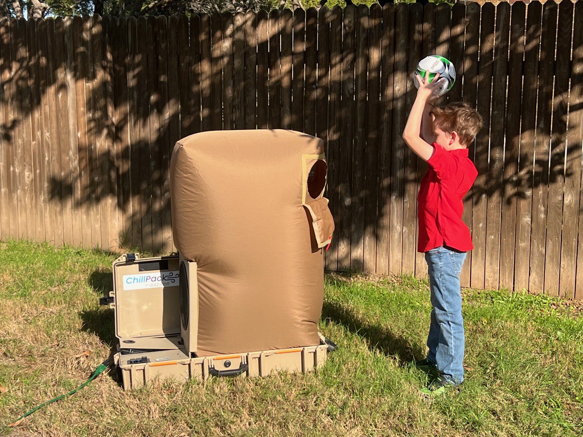 Boy throwing soccer ball at padded target